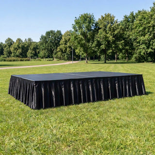 Black outdoor stage platform on grass in a park setting