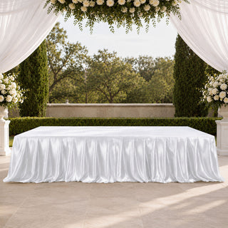 Elegant outdoor wedding table with white draped tablecloth and floral arch