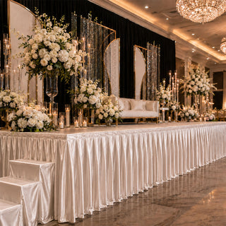 Elegant wedding stage decor with white floral arrangements and candlelit backdrop