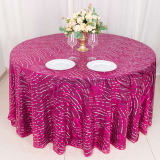 Round pink patterned tablecloth with plates and floral centerpiece.