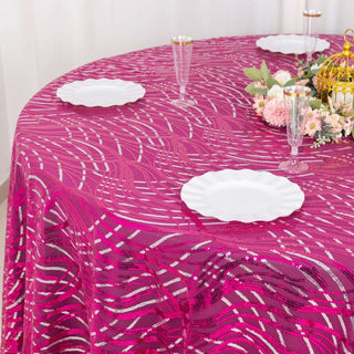 Pink patterned tablecloth with white plates and floral centerpiece.