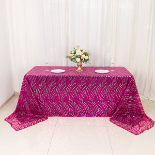 Pink patterned tablecloth draped over a table with a floral centerpiece.