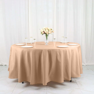 Round beige tablecloth on a dining table set for an elegant event.