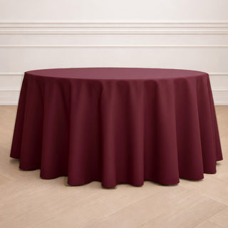 Burgundy round tablecloth on a wooden floor.