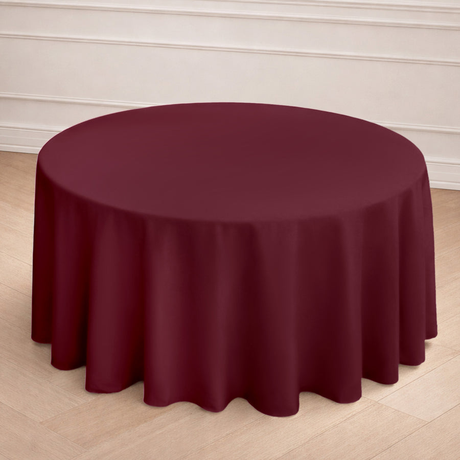 Round burgundy tablecloth draped over a table in a stylish setting.