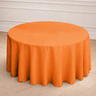 Round orange tablecloth on a wooden floor.