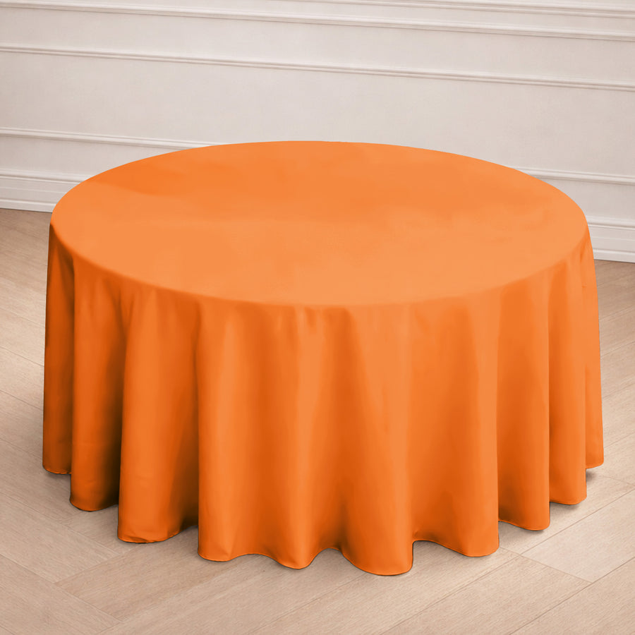 Round orange tablecloth on a wooden floor.