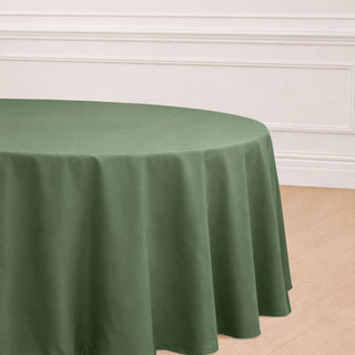 Round olive green tablecloth draped over a table in a bright setting.