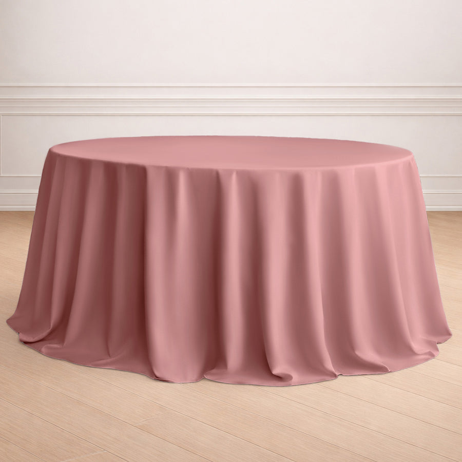 Round pink tablecloth draped over a circular table in a staged setting.