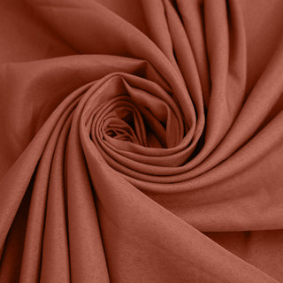 Rust-colored fabric rolled in a spiral pattern. #whtbkgd