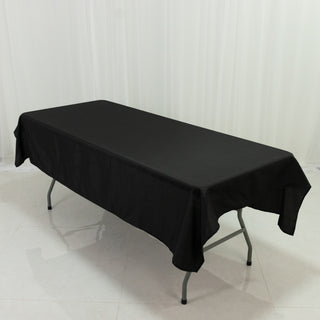 Black tablecloth draped over a folding table on a plain background.