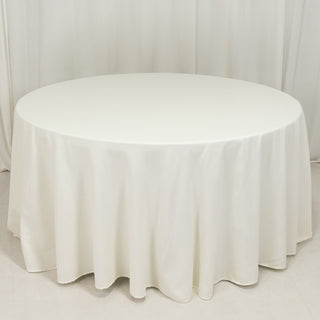 Round white table with a draped tablecloth in a studio setting.