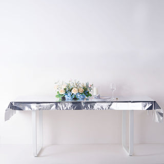 Elegant silver tablecloth with floral arrangement and glass on a table.