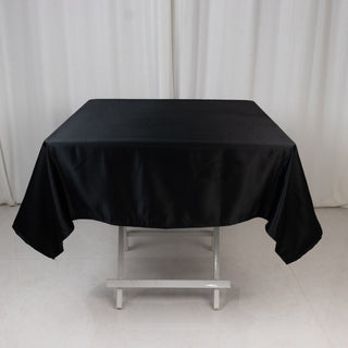 Black satin tablecloth on a folding table.
