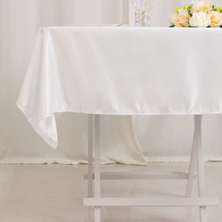 Elegant white tablecloth draped over a simple wooden table with floral centerpiece.