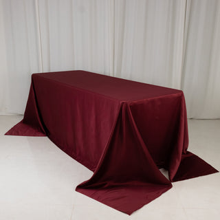 Burgundy tablecloth draped over a table on a neutral backdrop.
