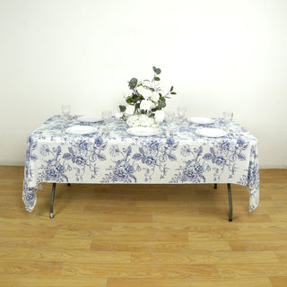 Floral tablecloth on a dining table set for a meal with plates and glasses.