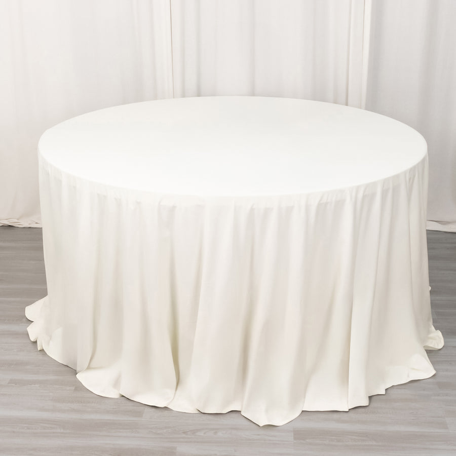 Round white table with a draped tablecloth in a studio setting.