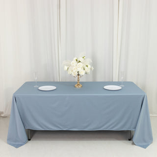Elegant blue tablecloth with white plates and floral centerpiece on a clean backdrop.