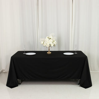 Elegant black table setting with a floral centerpiece and white plates.