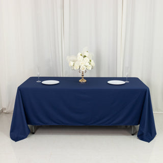 Elegant navy tablecloth with floral centerpiece and plates on a dining table.