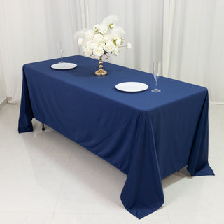 Navy blue tablecloth with white plates and floral centerpiece on a table.