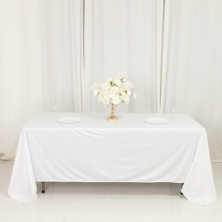 Elegant white table setup with floral centerpiece and empty plates.