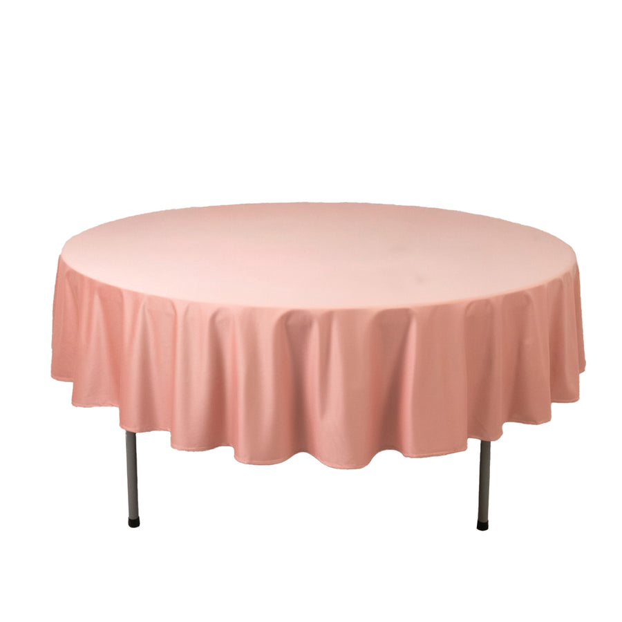 Round pink tablecloth draped over a circular table on a plain backdrop