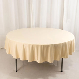 Round cream table with a smooth tablecloth, showcasing its elegant design.