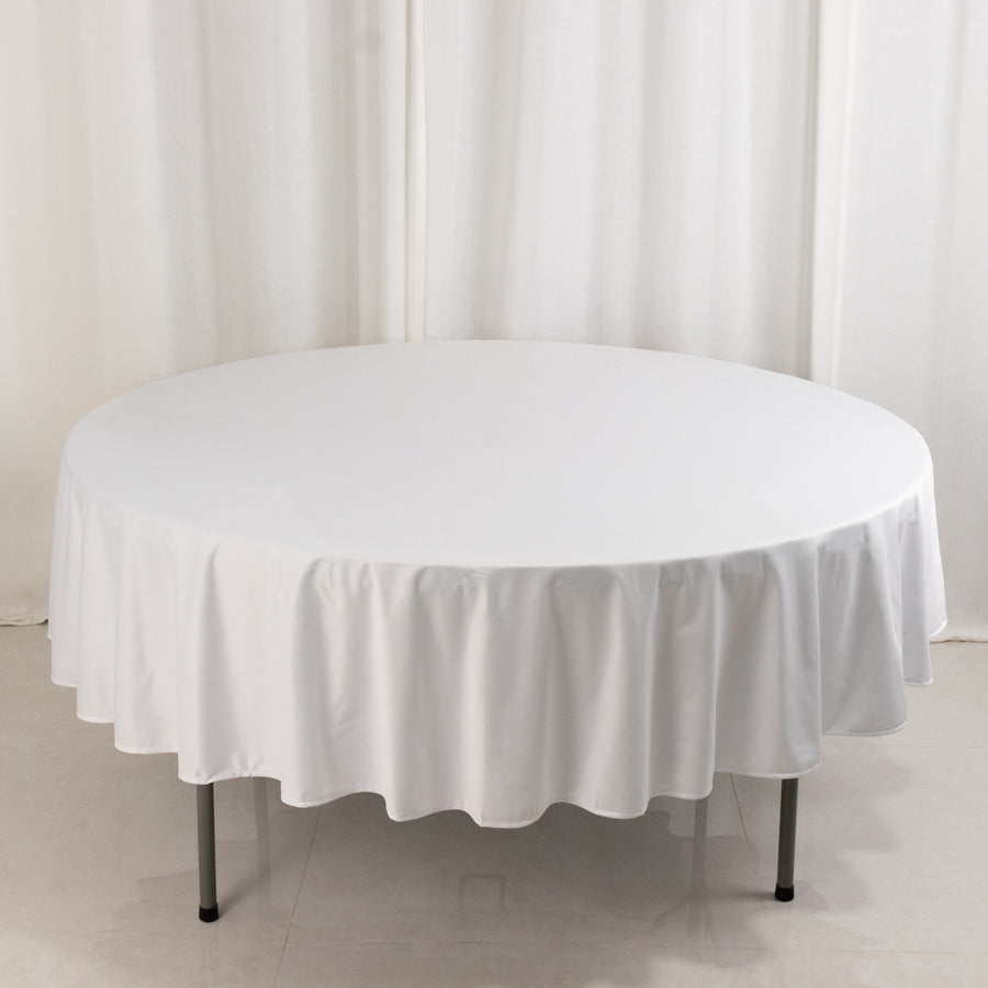Round white table with a fitted tablecloth in a studio setting.