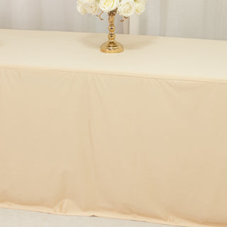 Beige tablecloth draped over a table with a gold candlestick and white roses.