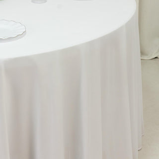 White tablecloth draped over a round table in a minimalistic setting.