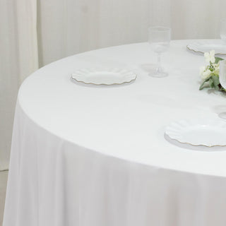 Elegant round table set with white plates and crystal glasses.