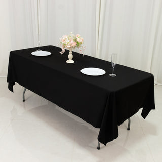 Elegant black table setup with dishes and floral centerpiece.