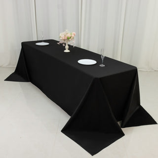 Black tablecloth draped elegantly on a long table with plates and glasses.