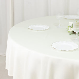 Elegant round table set with white scalloped plates and decorative flowers.