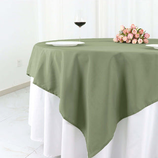 Olive green tablecloth draped elegantly on a round table with flowers and wine