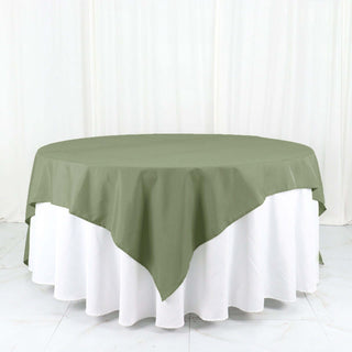Round olive green tablecloth draped over a white table.