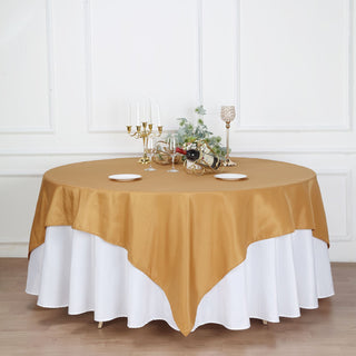 Elegant gold and white tablecloth draped over a round table with decorative settings.