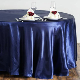 Navy satin tablecloth draped over a round table with elegant table settings.