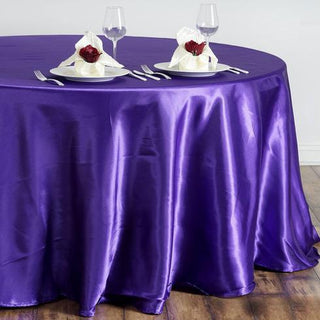 Purple round tablecloth draped elegantly on a table with fine dining setup.