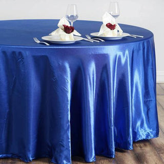 Blue satin tablecloth with elegant dinner setting and decorative napkins.