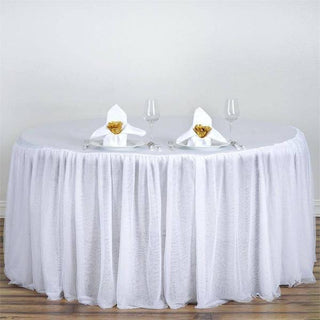 Elegant round table with white tablecloth, napkins, and glassware.