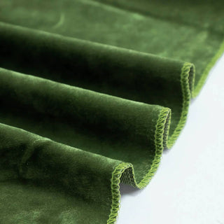 Green velvet fabric with pleated folds and stitched edges close-up
