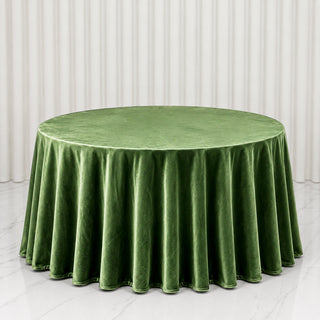 Round green velvet tablecloth on a banquet table with draped white backdrop