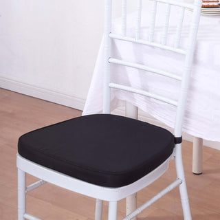Black cushioned chair seat on a white wooden chair in a staged setting.