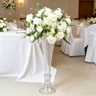 Elegant white wedding floral centerpiece in tall glass vase at reception table