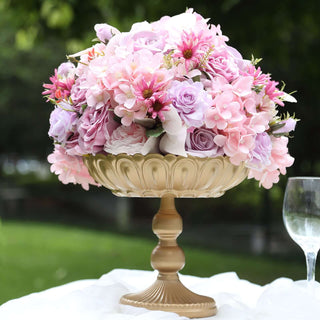Gold pedestal vase filled with pink and purple flowers.