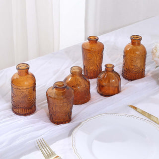 Set of six amber glass bottles on a table.