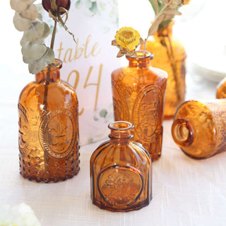 Vintage amber glass bottles with dried flowers arranged on a table.